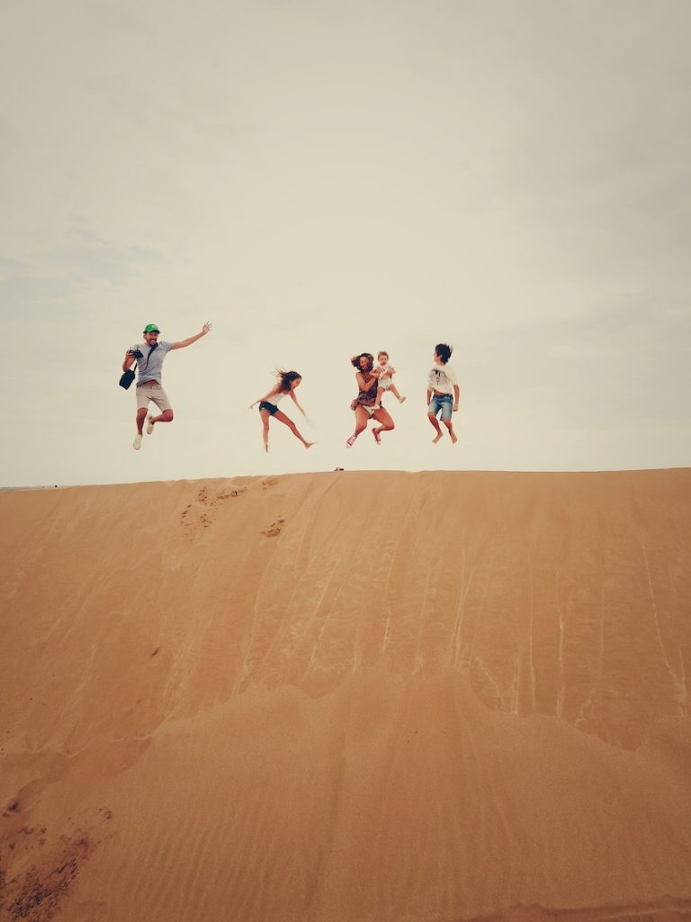 people jumping on sand